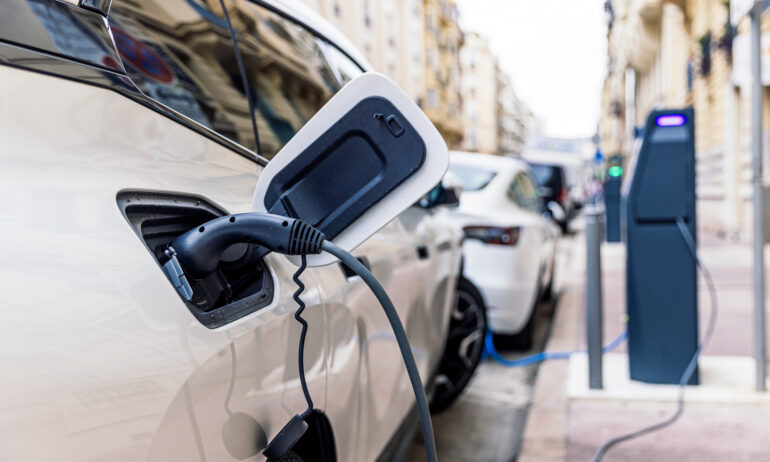 Hybrid car parked on street and plugged into charger.